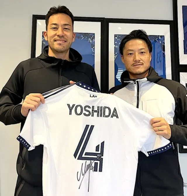 吉田麻也選手のサイン入りユニフォームを持つ吉田選手と木谷将志